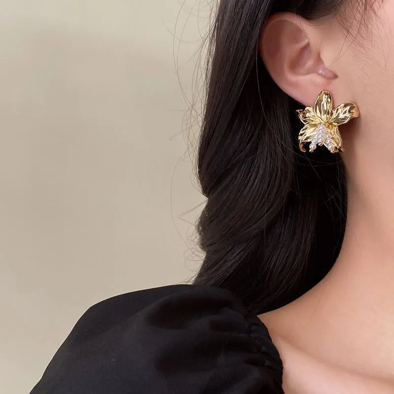 Gold H1795 metal flower earrings with a pearl centre, showing exaggerated floral shape and niche style.