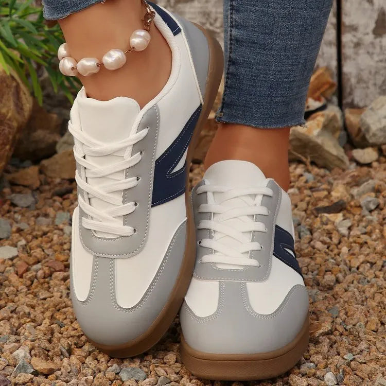 Blue women's low-top hiking shoes with flat rubber sole and lace-up front on artificial grass.