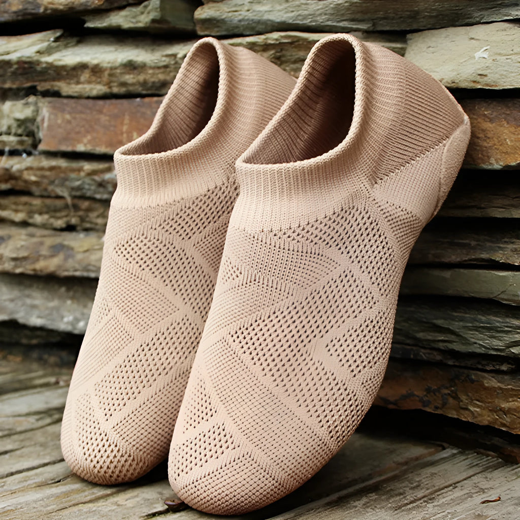 Camel colour dance yoga shoes with cotton mesh upper and leather sole on a plain background.