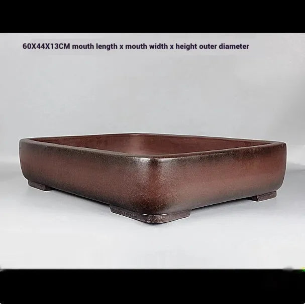 Handmade antique-style rectangular purple clay flower pot on a wooden surface.