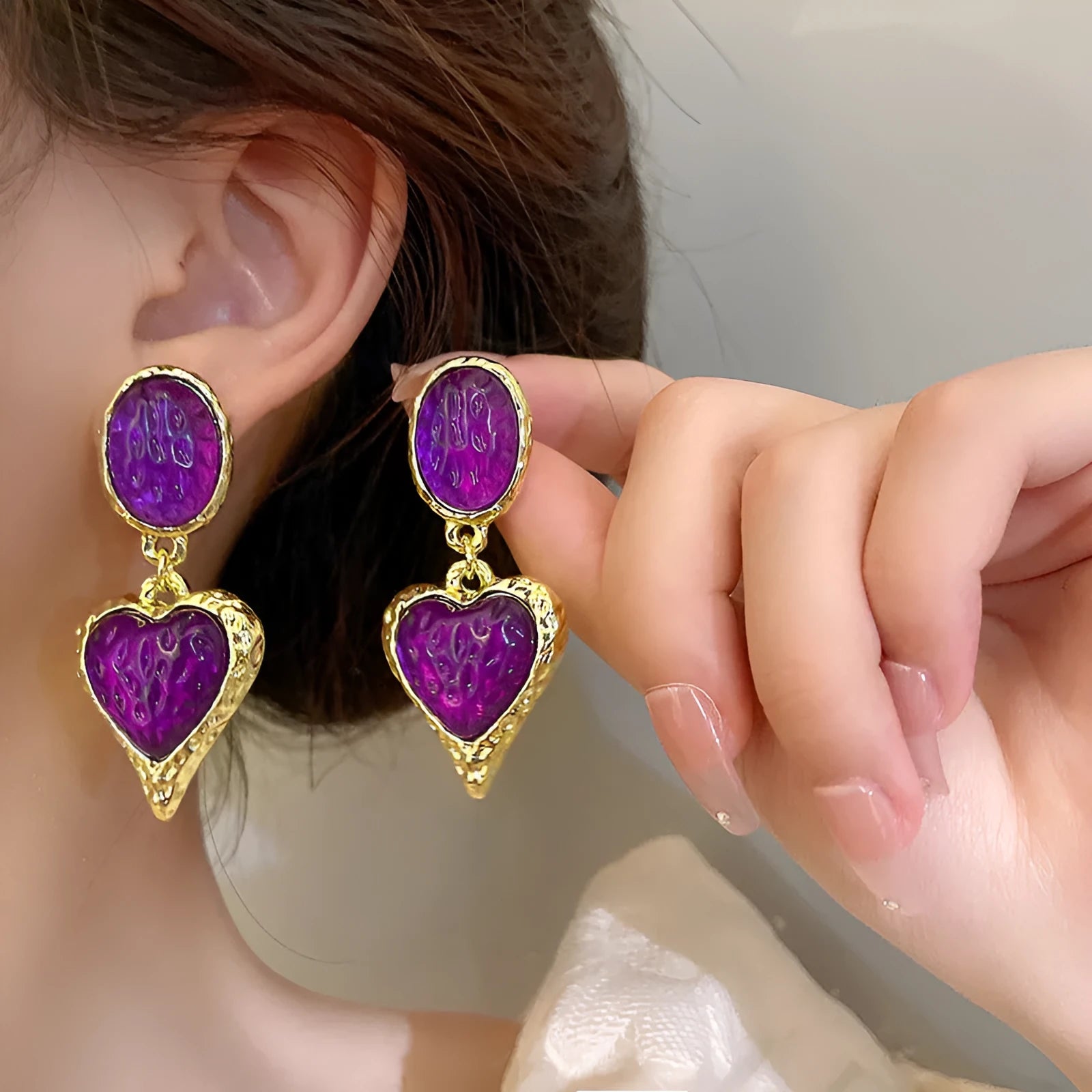 A pair of oval-shaped, pleated love heart stud earrings in alloy, shown in various colours.