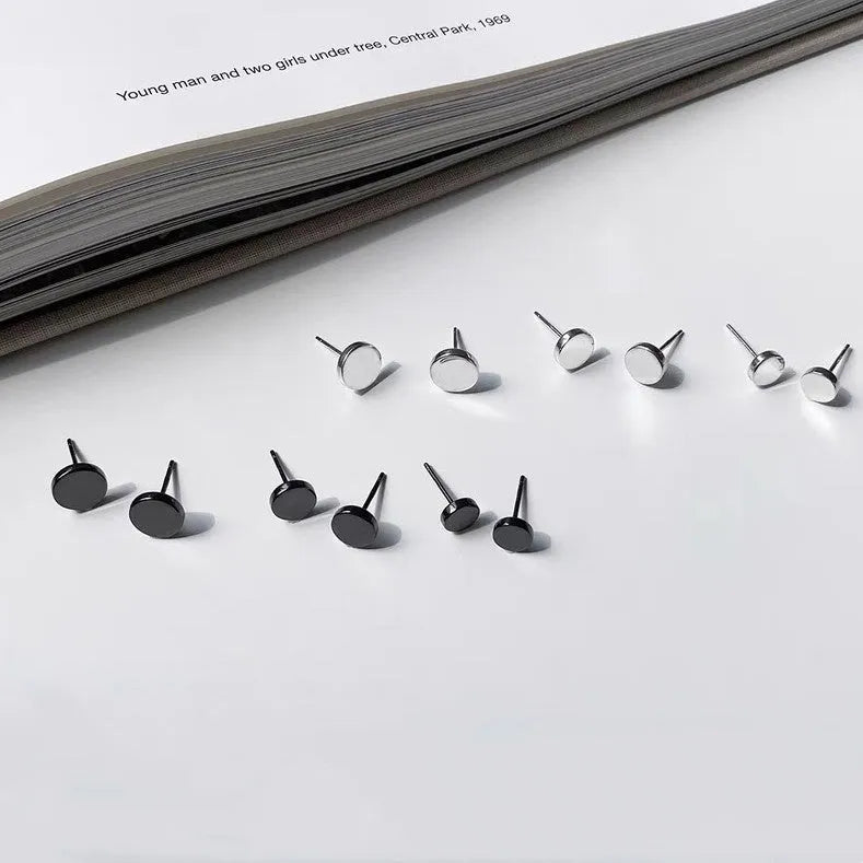 A pair of S999 sterling silver round flat stud earrings on a plain background, showing silver and black colour options.