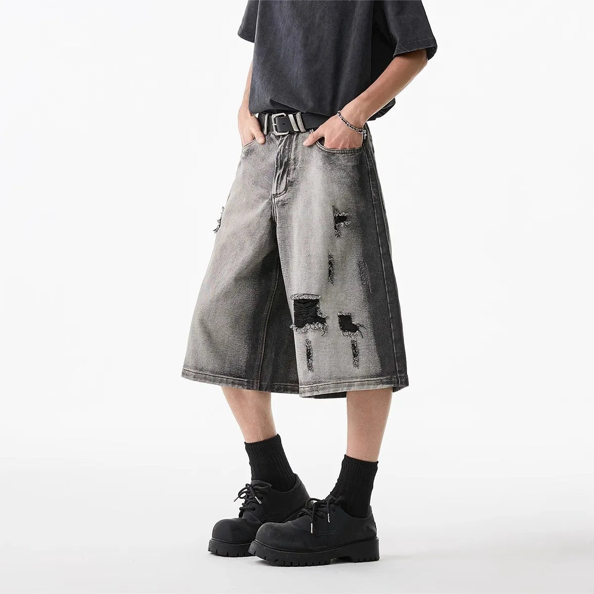 Gray distressed denim shorts with hole detailing, loose cropped fit on a plain background.