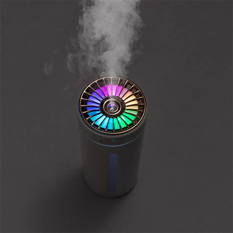 Black portable ultrasonic humidifier with colourful LED lights, shown next to a USB cable on a desktop.