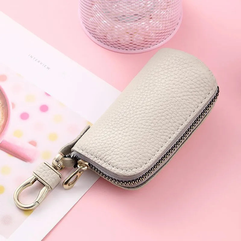 Simple black PU leather zipper key ring case on a grey background.