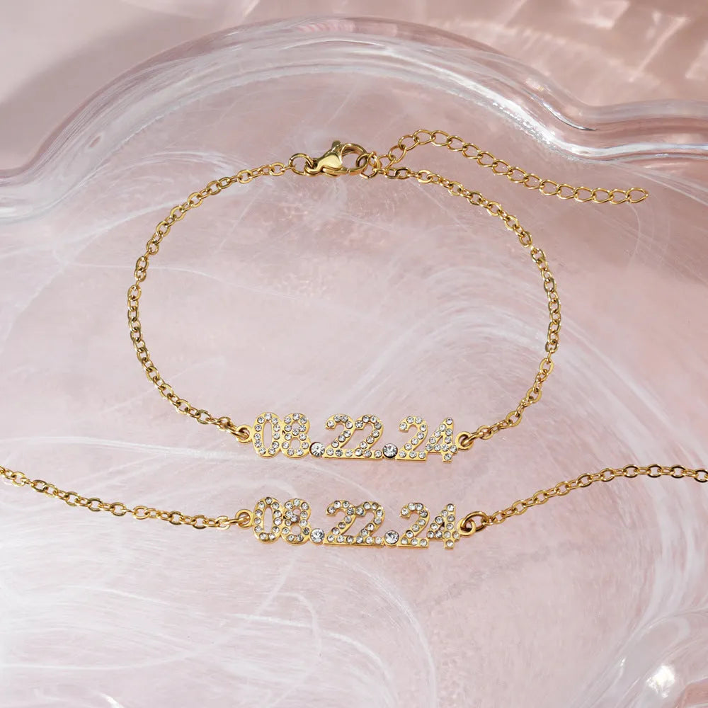 Stainless steel digital bracelet or necklace with diamond-set numbers on display, shown in gold colour.