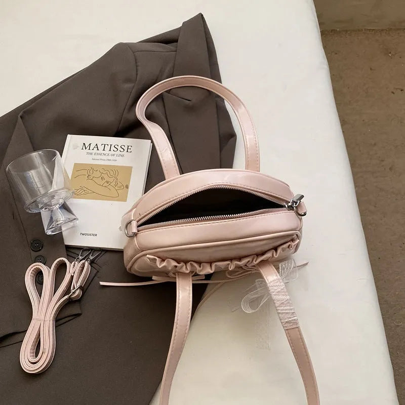 Milky white women's PU leather shoulder bag with a removable bandage bow and visible sewing thread detailing