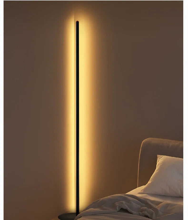 Modern simple vertical aluminium alloy floor lamp in silver, shown beside a sofa.